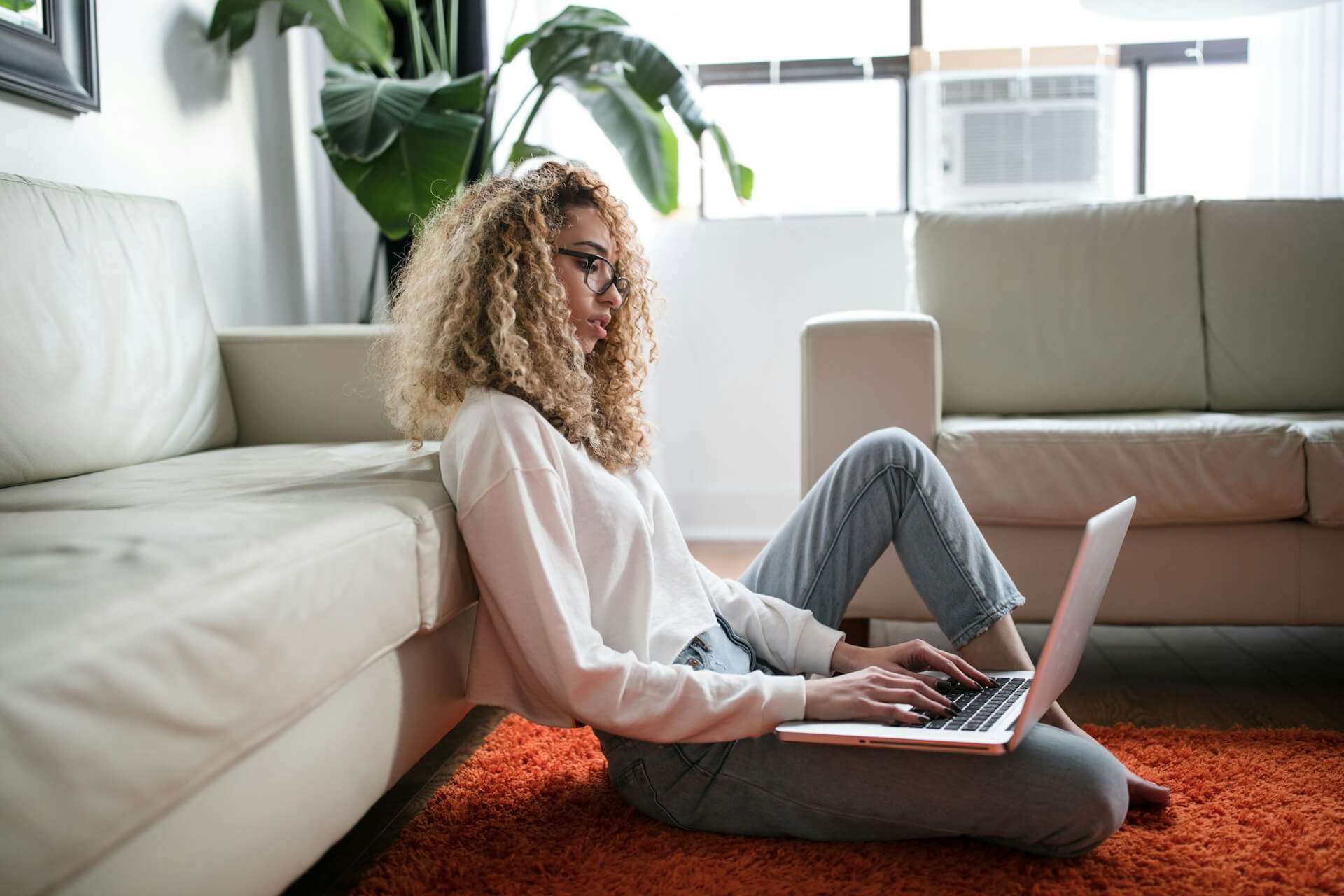 woman sitting on living room floor using a laptop